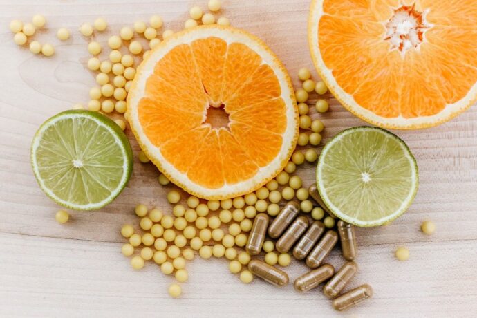Skivade apelsiner, limefrukter samt kosttillskott i form av kapslar och små gula piller.