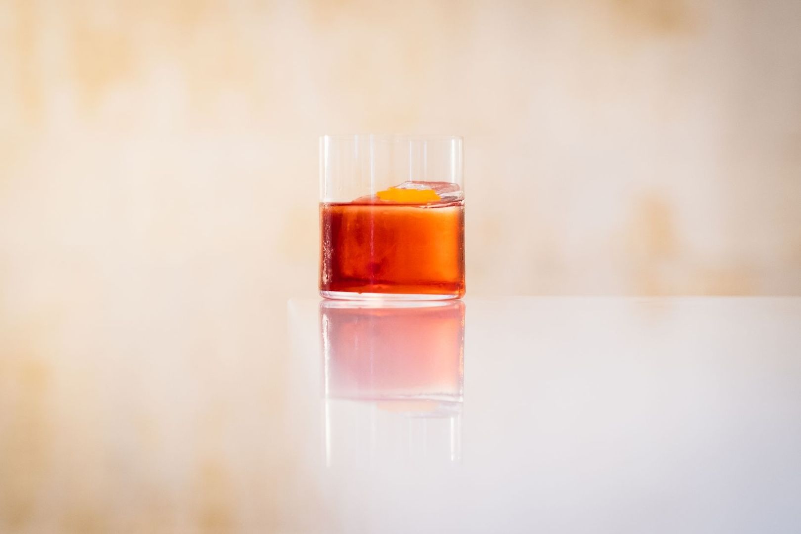 Röd aperitif i ett lågt glas med apelsinzest och isbit